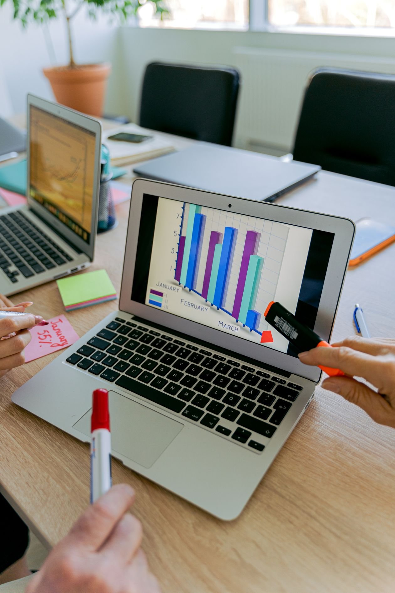 Business meeting reviewing financial graphs, laptop and documents on a table