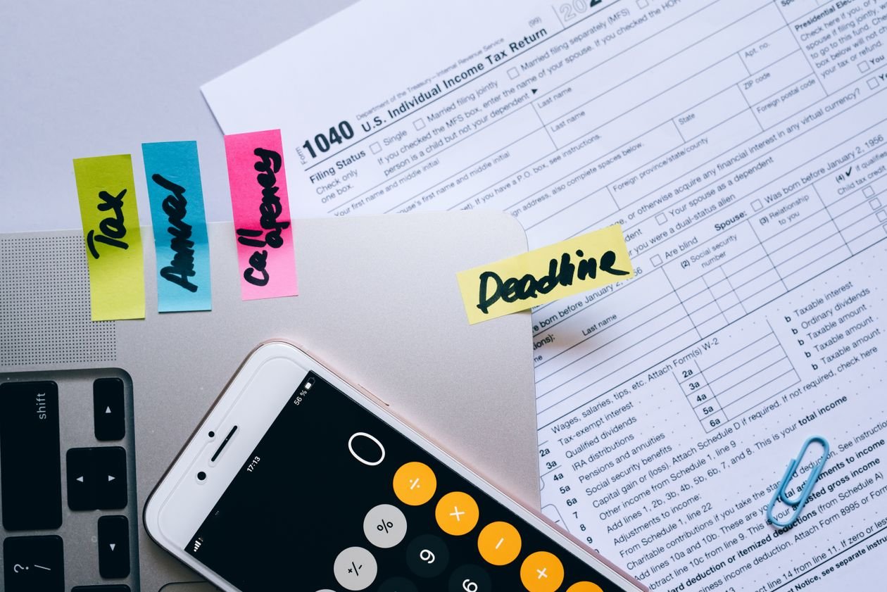 Office desk with tax paperwork, calculator app on a smartphone and sticky notes