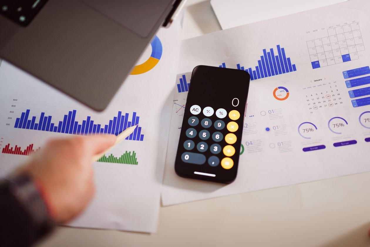 Business desk with laptop, calculator and graphs used to review company profits and tax